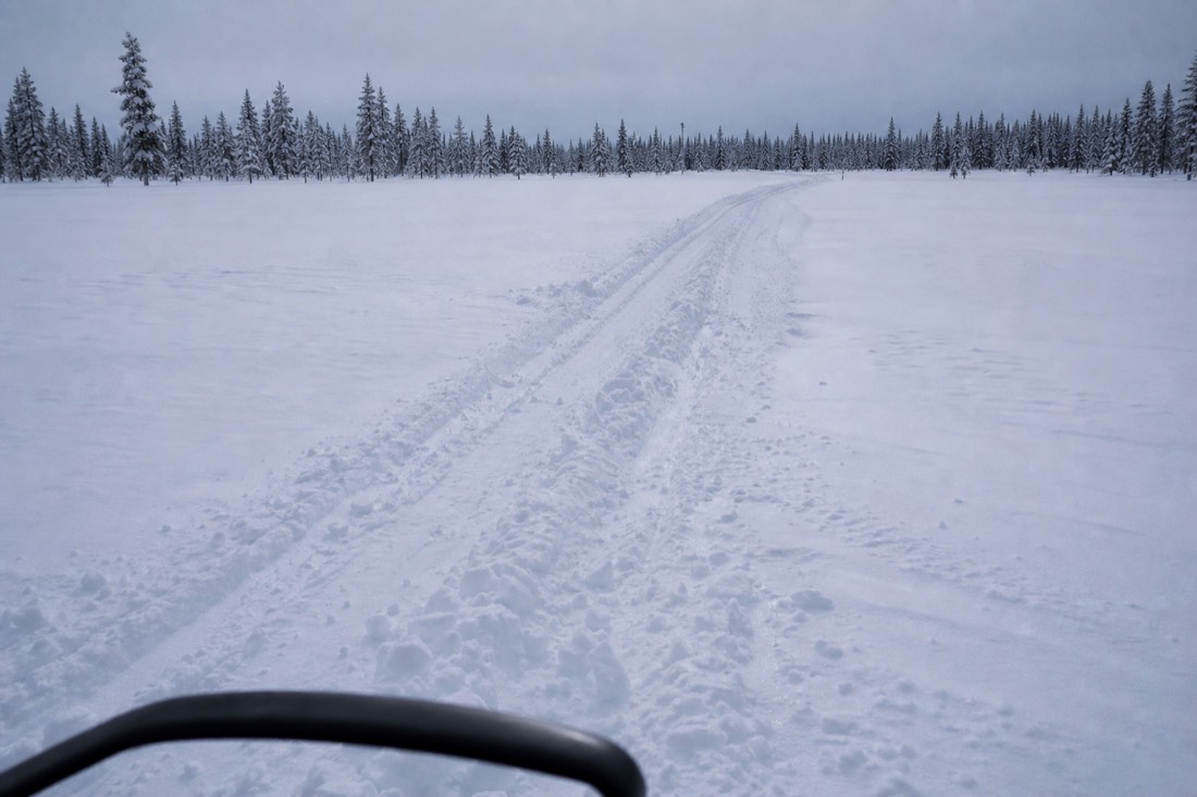 Snowmobile tracks across an open snowfield in Finnish Lapland