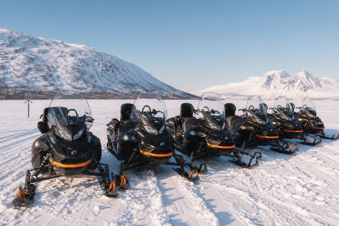 A group of modern snowmobiles parked in formation on deep snow, mountains visible in distance, Lapland winter landscape