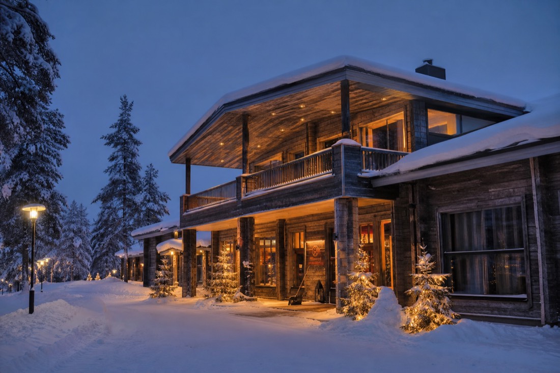 A luxury Lapland hotel exterior in deep snow at twilight, warm glowing windows, wooden Nordic architecture