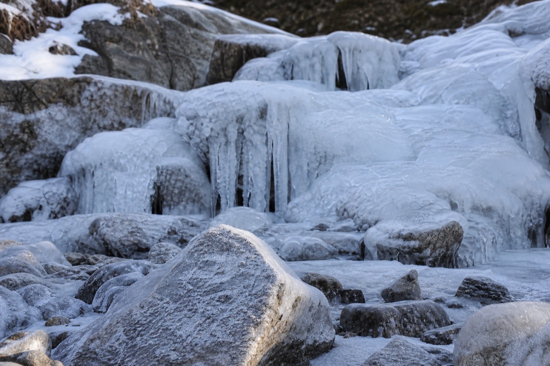 Ein zugefrorener Wasserfall und vereiste Felsen in einem Lappland-Bachbett